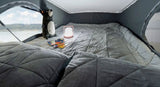Cozy pop-top bed in an RV rental with a scenic lake view, featuring plush grey bedding, a playful bear, and a night light.