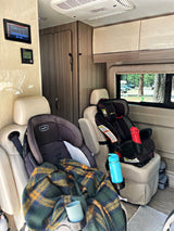 Family-friendly RV rental interior featuring two car seats, cozy blanket, and control panels for comfortable family travel.