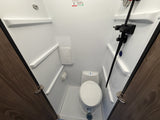 Inside an rv rental: a compact bathroom with white toilet, shower, & molded shelves, designed for space-saving.