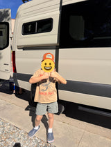 Excited child gives thumbs up beside a cream RV rental camper van, perfect for family road trips.