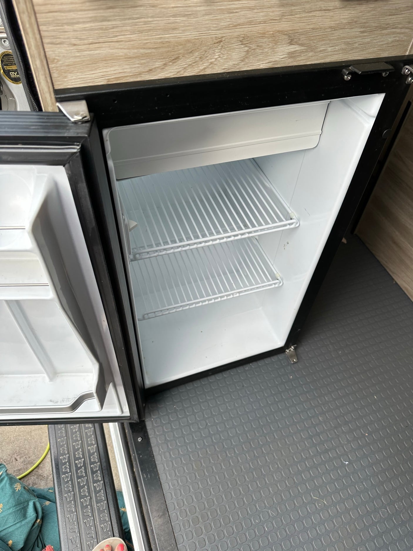 Inside an RV rental: a compact, open mini-fridge with white wire shelves, ready for your travel snacks and drinks.