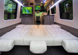 Luxury RV rental interior with a spacious, comfortable bed, dual TVs, and elegant wood paneling, perfect for your next adventure.