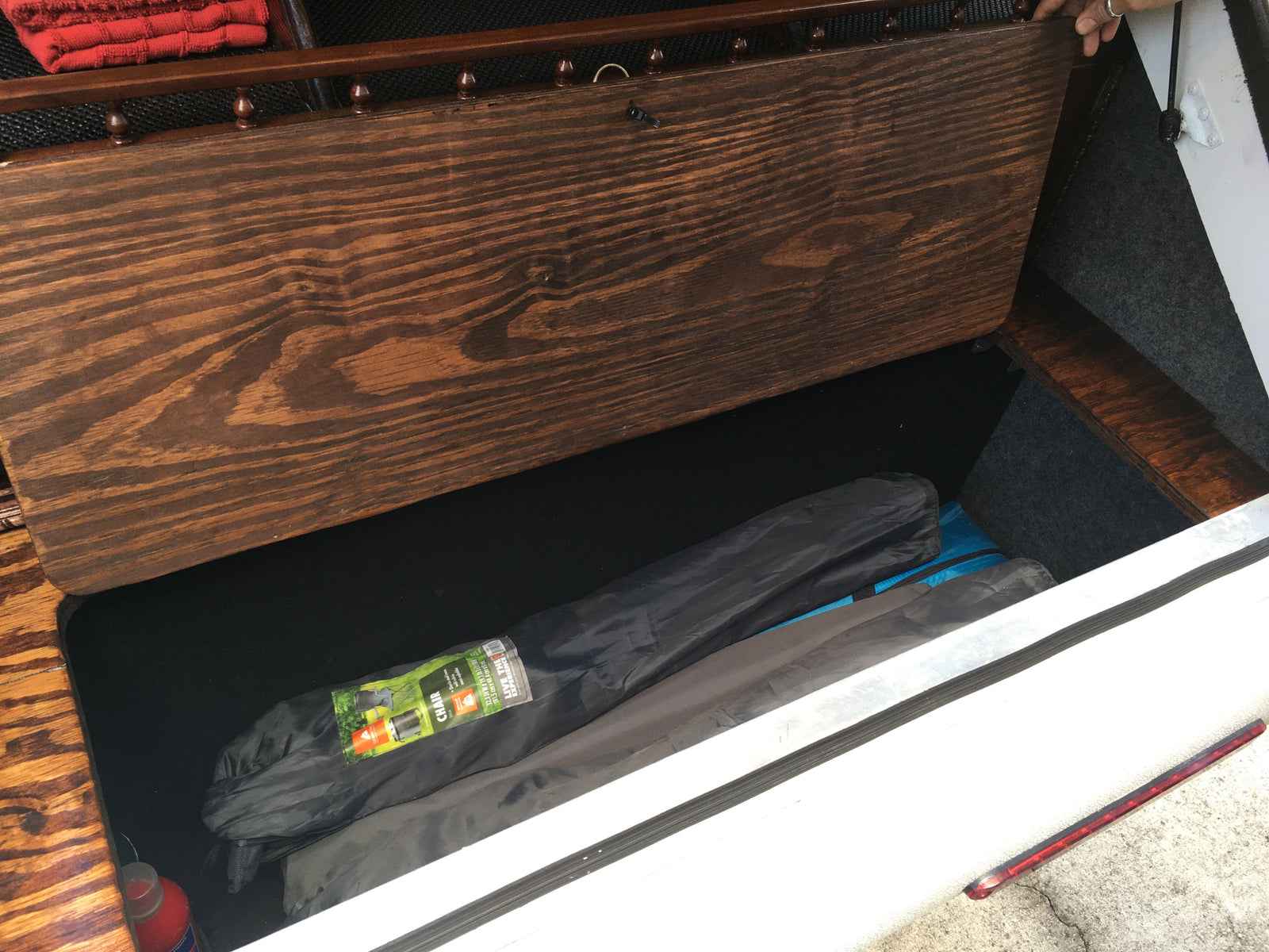 Open RV rental storage bench with two folded camping chairs inside. Efficient space for your next adventure.