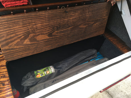 Open RV rental storage bench with two folded camping chairs inside. Efficient space for your next adventure.