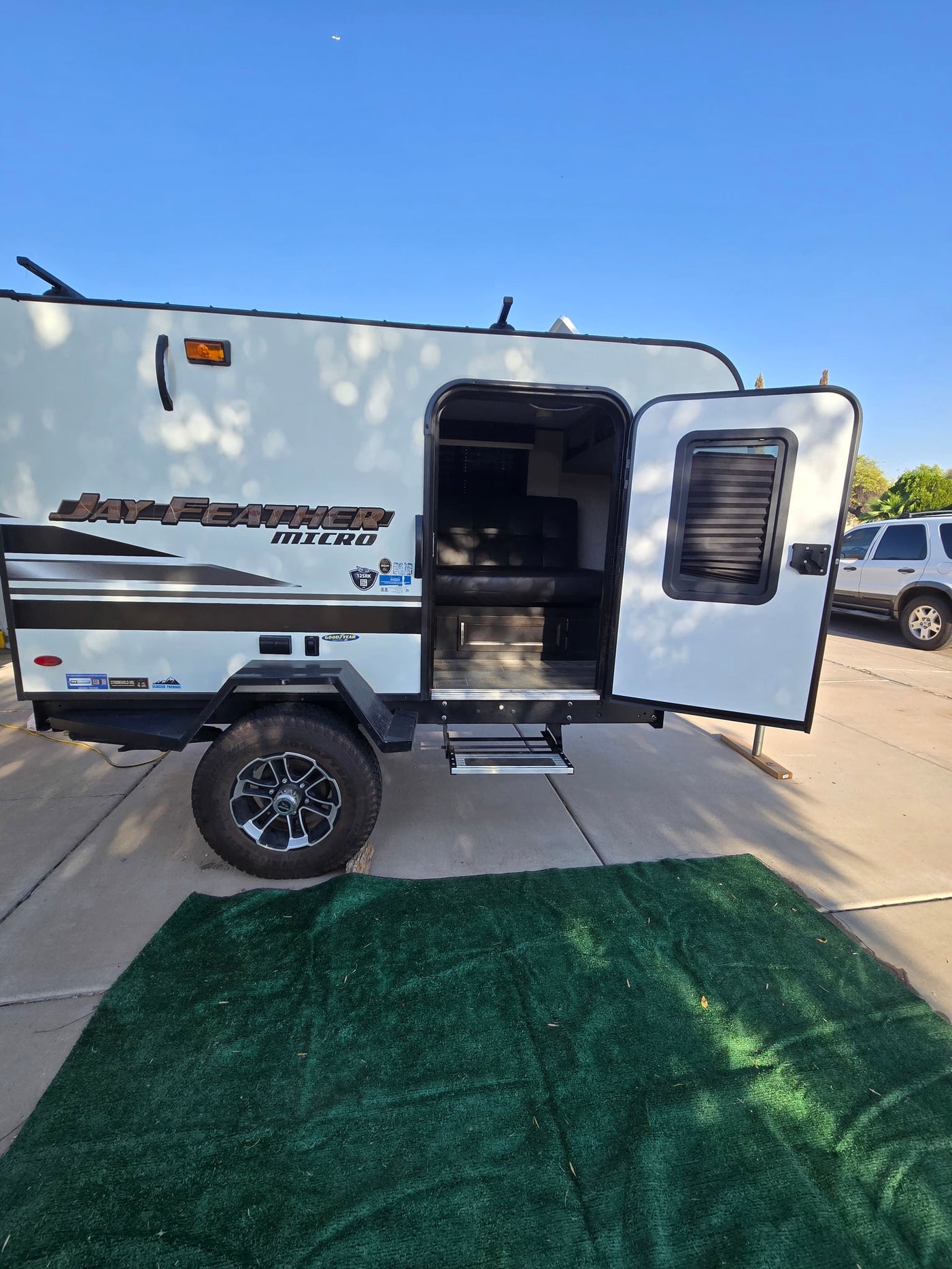  set up on a sunny driveway.|Jayco travel trailer hitched to SUV at a dirt forest campsite — photo 3