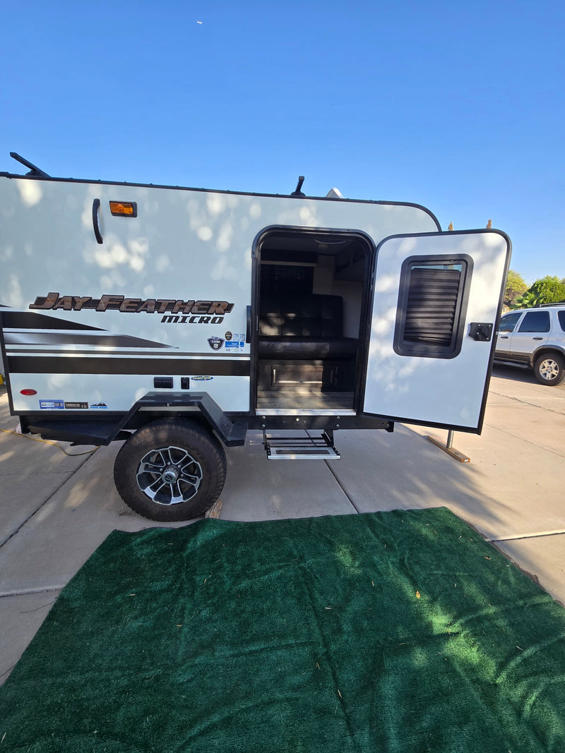  set up on a sunny driveway.|Jayco travel trailer hitched to SUV at a dirt forest campsite — photo 3