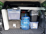 Efficiently packed trunk for your next rv rental trip: storage bins, water jug, and kitchen set ready to go.
