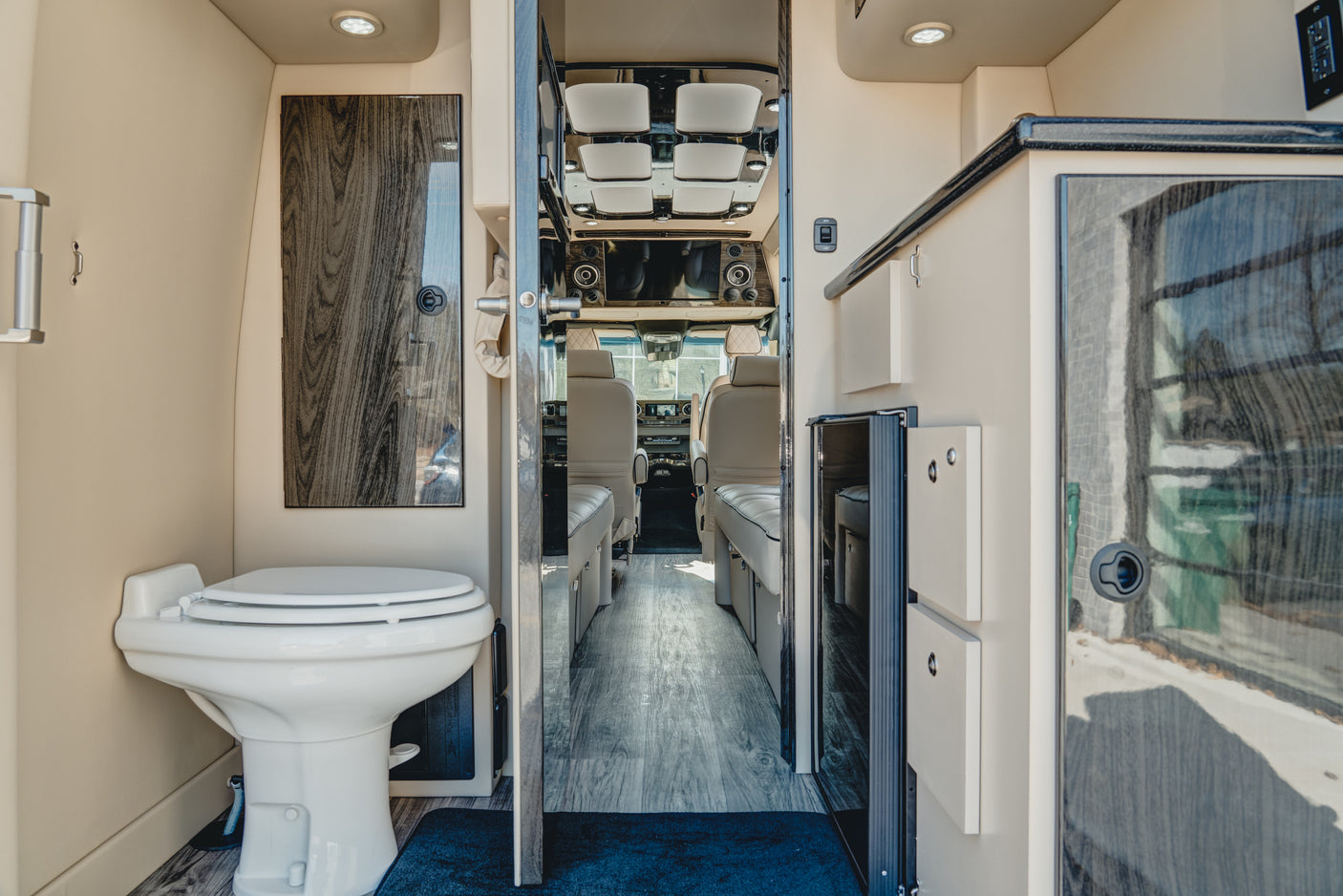 Step inside this RV rental: a modern interior with a compact toilet, an open aisle, and the driver's cabin visible upfront.