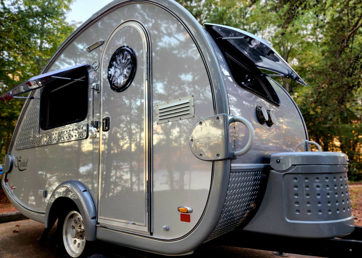 Sleek grey T@B teardrop RV rental featuring a rounded design, pop-out windows, and front storage. Perfect for outdoor adventures.
