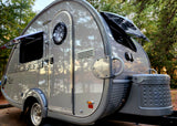 Sleek grey T@B teardrop RV rental featuring a rounded design, pop-out windows, and front storage. Perfect for outdoor adventures.