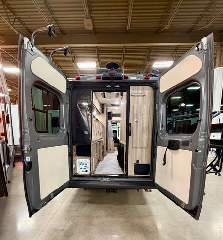 Step inside this RV rental! Rear doors of a grey camper van open wide, showcasing its comfortable and compact interior.