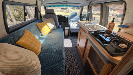 Interior of a comfortable rv rental with kitchen, spacious seating, and large windows revealing the outdoors.