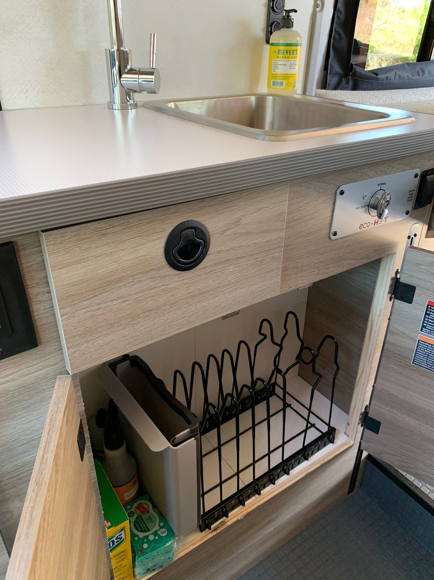 RV rental kitchen: stainless steel sink, eco-HOT water control, and under-counter storage with dish rack & cleaning supplies.