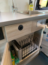 RV rental kitchen: stainless steel sink, eco-HOT water control, and under-counter storage with dish rack & cleaning supplies.