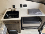This RV rental kitchenette features a sink, thermostat, charging station, and an EverChill portable cooler/fridge.