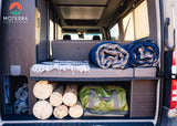 Well-organized rear storage in an RV rental, featuring bedding, firewood, and gear for your next adventure.