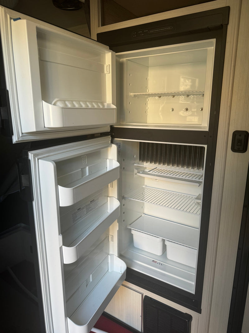 Inside a clean, empty RV refrigerator, ready for your rv rental. Both doors are open, revealing shelves and door bins. — photo 7