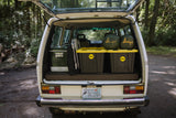 RV rental camper van packed for adventure! Rear view shows open trunk with cooler, Slumbojack bags, and storage bins.