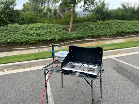 Portable outdoor kitchen setup with Coleman camp stove, sink, and table, perfect for your RV rental adventure.