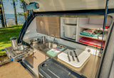 This RV rental's teardrop outdoor kitchen features a sink, slide-out stove, cooler, and storage.