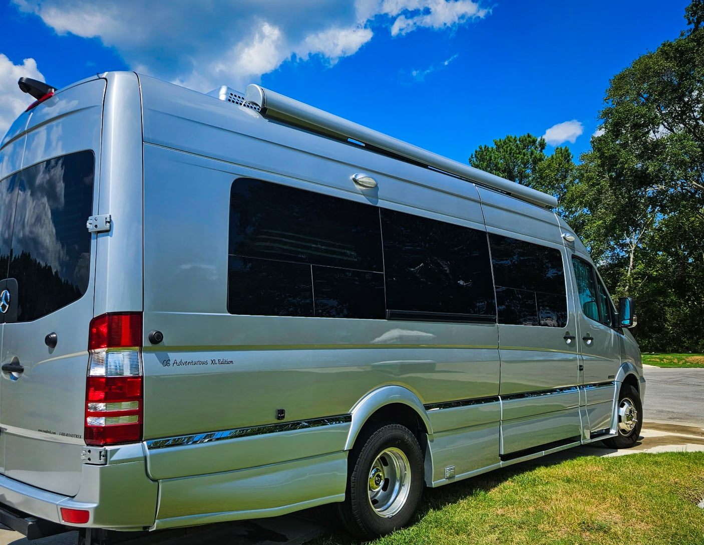 Silver Roadtrek CS Adventurous XL RV rental parked under a blue sky. Perfect camper van for your next adventure or road trip.