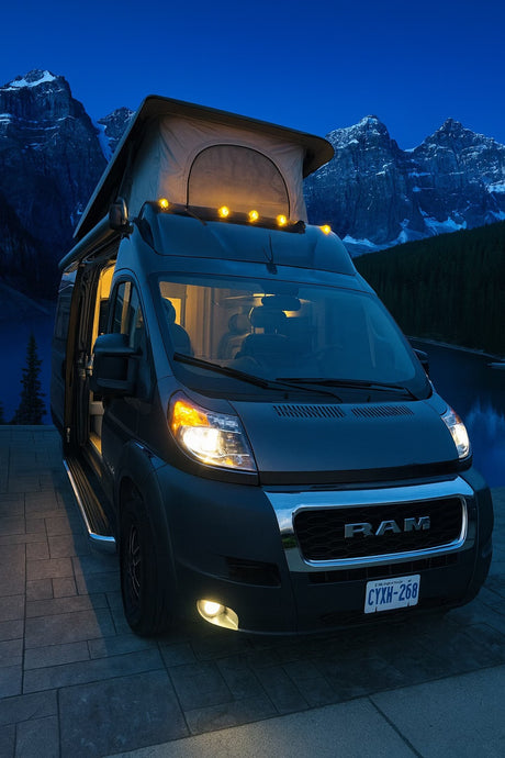 Experience nature! This dark RV rental camper van, pop-top open, glows at dusk by a lake & snowy mountains. Perfect for adventure.