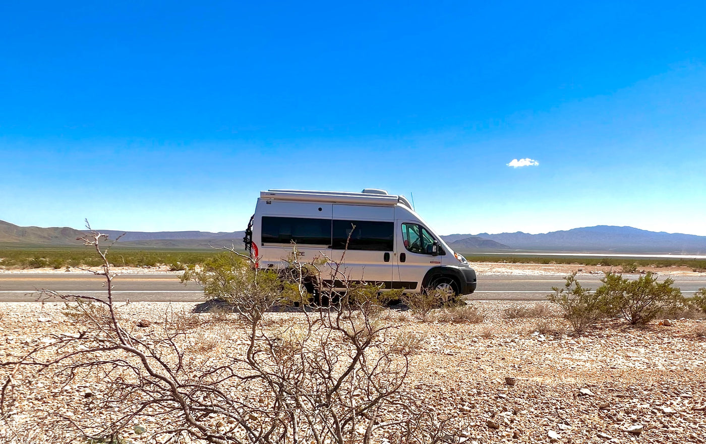  parked overlooking mountains.|Silver RV rental parked on a desert road with mountains under a clear blue sky — photo 6