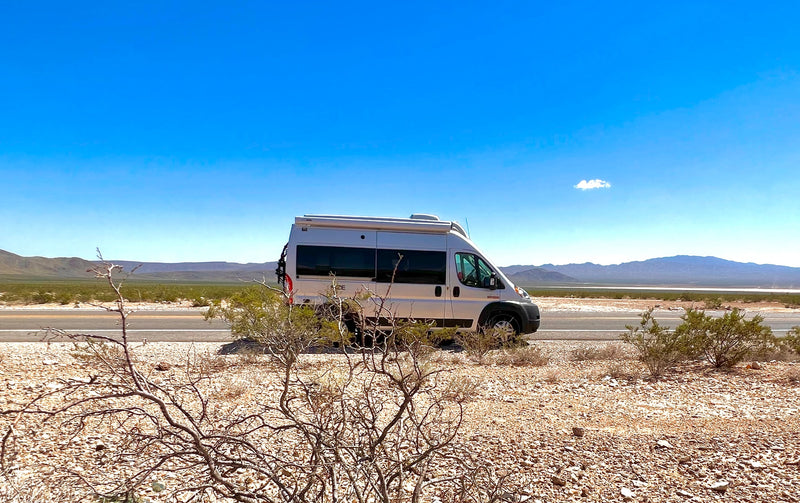  parked overlooking mountains.|Silver RV rental parked on a desert road with mountains under a clear blue sky — photo 6