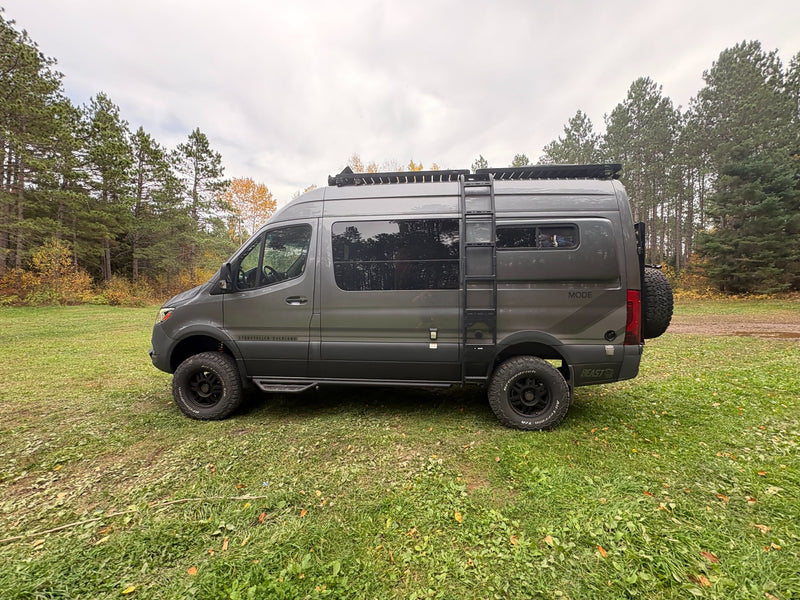  is parked in a beautiful autumn forest clearing with fall foliage.|This gray Storyteller Overland MODE **rv rental** — photo 9