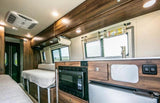 Inside an RV rental: a well-equipped kitchen with microwave, fridge & sink, and comfortable living/bedding for travel.