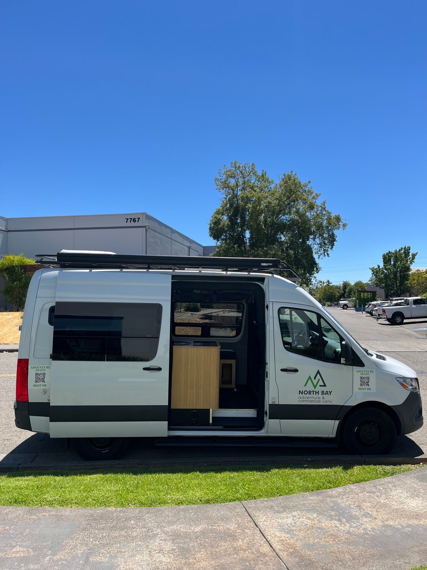 White North Bay RV rental conversion van with side door open, showcasing a custom-built interior. Adventure awaits! — photo 2