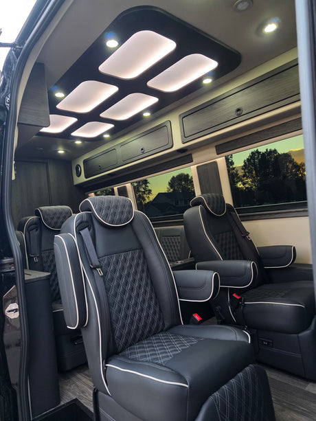 Luxurious RV rental interior: custom ceiling lighting, comfortable diamond-stitched seats, and elegant wood-look flooring.