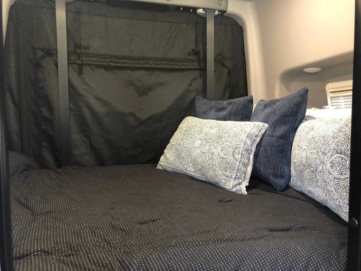 Comfortable RV rental bed with patterned comforter & throw pillows in a cozy interior, ideal for relaxation. — photo 7