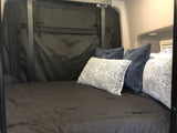 Comfortable RV rental bed with patterned comforter & throw pillows in a cozy interior, ideal for relaxation.