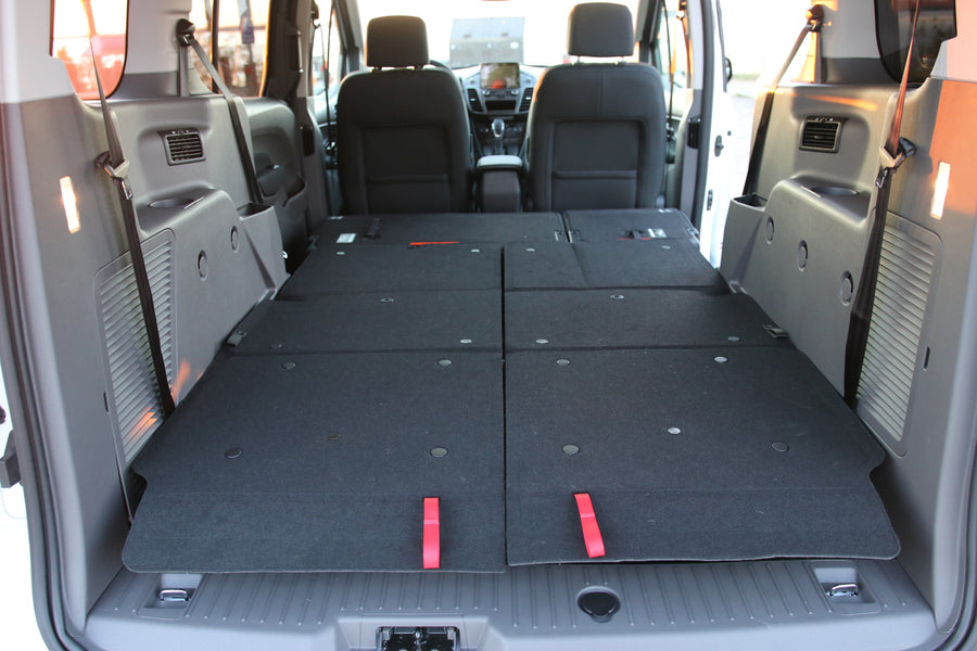 RV rental interior with rear seats folded flat, revealing a versatile cargo or sleeping area in the van.