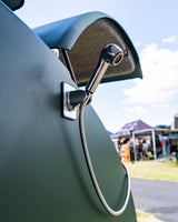 RV rental outdoor shower: chrome head, flexible hose, mounted on a dark green vehicle. Great for camping trips.