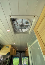 Looking up at a modern RV rental ceiling with a white slatted design, a large central vent fan, and recessed LED lights.