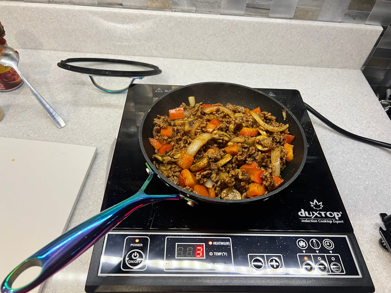 Sautéing ground meat, onions, peppers, and mushrooms on an induction cooktop, ideal for an RV rental kitchen. — photo 10