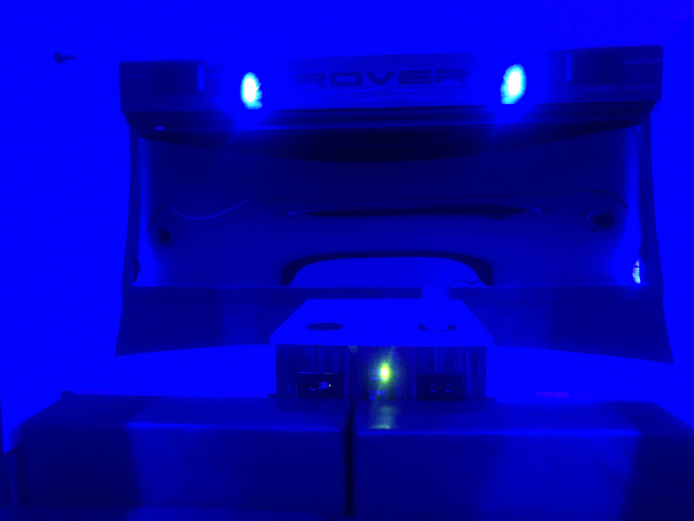 Blue-lit RV rental interior featuring a 'ROVER' display, illuminated controls, and a prominent green light.