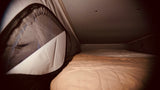 Cozy sleeping area inside an RV rental. Features a comfortable bed & mesh window in a pop-top camper.