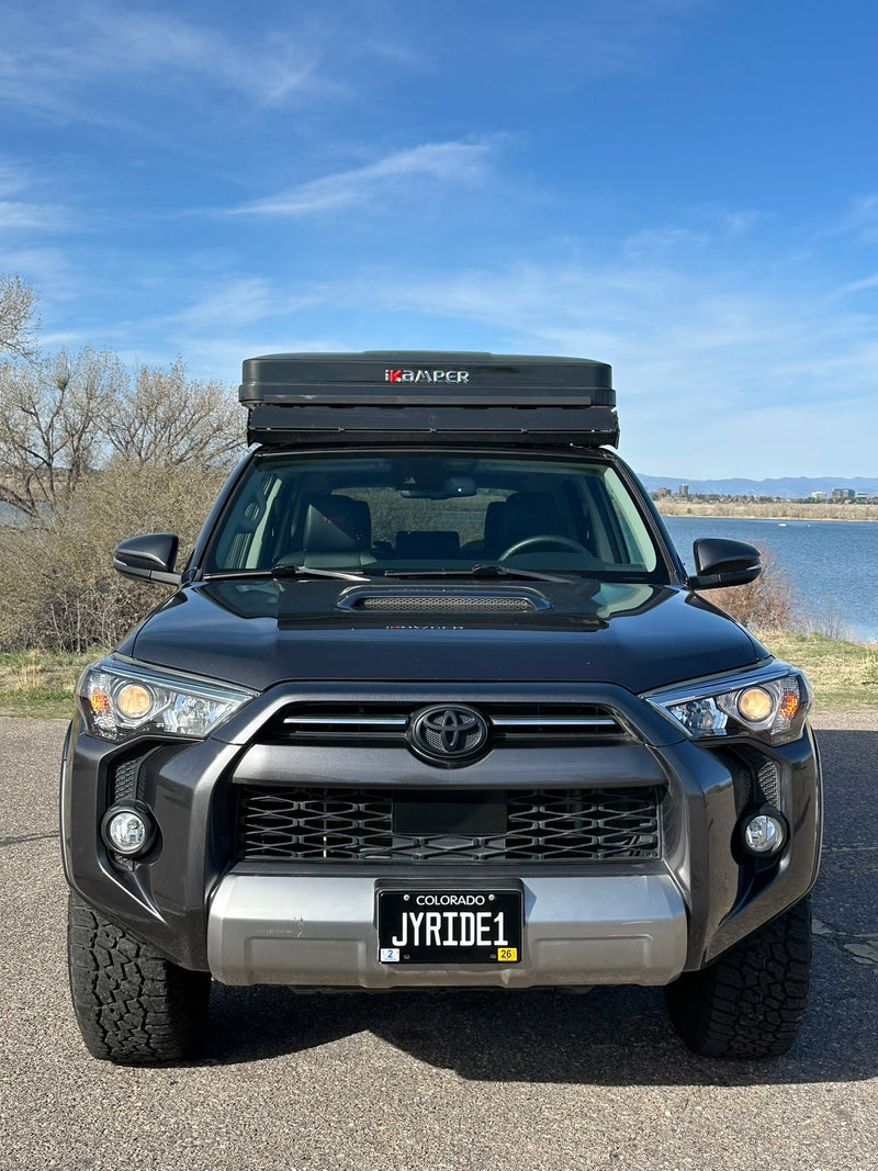  parked lakeside under blue skies.|Side view of a dark gray Toyota 4Runner SUV with a rooftop tent by a lake. Perfect for adventure — photo 6