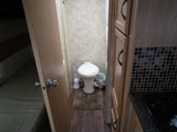 Inside an RV rental: a compact bathroom with toilet, comfortable bed area, and efficient kitchen with stovetop & cabinets.