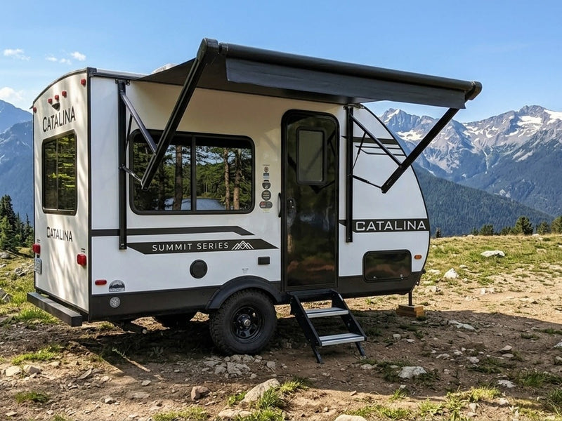 RV rental: A white Catalina Summit Series travel trailer with an extended awning in a scenic mountain landscape.|This RV rental floor plan (134RKX) details an interior with a queen bed — photo 1