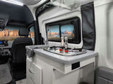 Experience adventure in this RV rental! Features a compact kitchen with stove, sink, and a scenic desert landscape view.