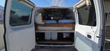 RV rental van interior with a bed, under-bed storage, and open rear doors revealing a snowy landscape outside.