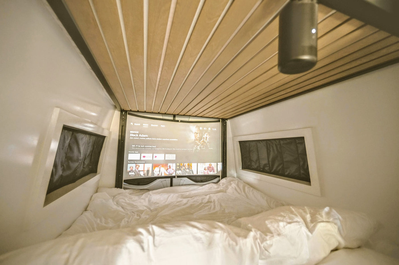 Cozy rv rental interior with bed, ceiling projector, and large screen displaying "Black Adam" for movie nights. Wi-Fi disconnected. — photo 12
