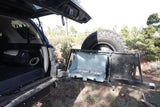 An RV rental-style vehicle with its rear hatch open, revealing a camp stove set up on a swing-out arm.