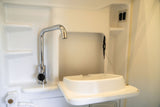 RV rental: Compact white wet bath with a chrome faucet and a hinged, space-saving sink.