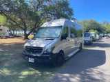 Hawaii RV rental: Silver Mercedes Sprinter van parked in a shaded campground with other vans under a clear sky.