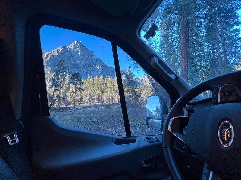 An rv rental provides a stunning view of a majestic mountain and pine forest through its passenger window under a clear sky. — photo 20